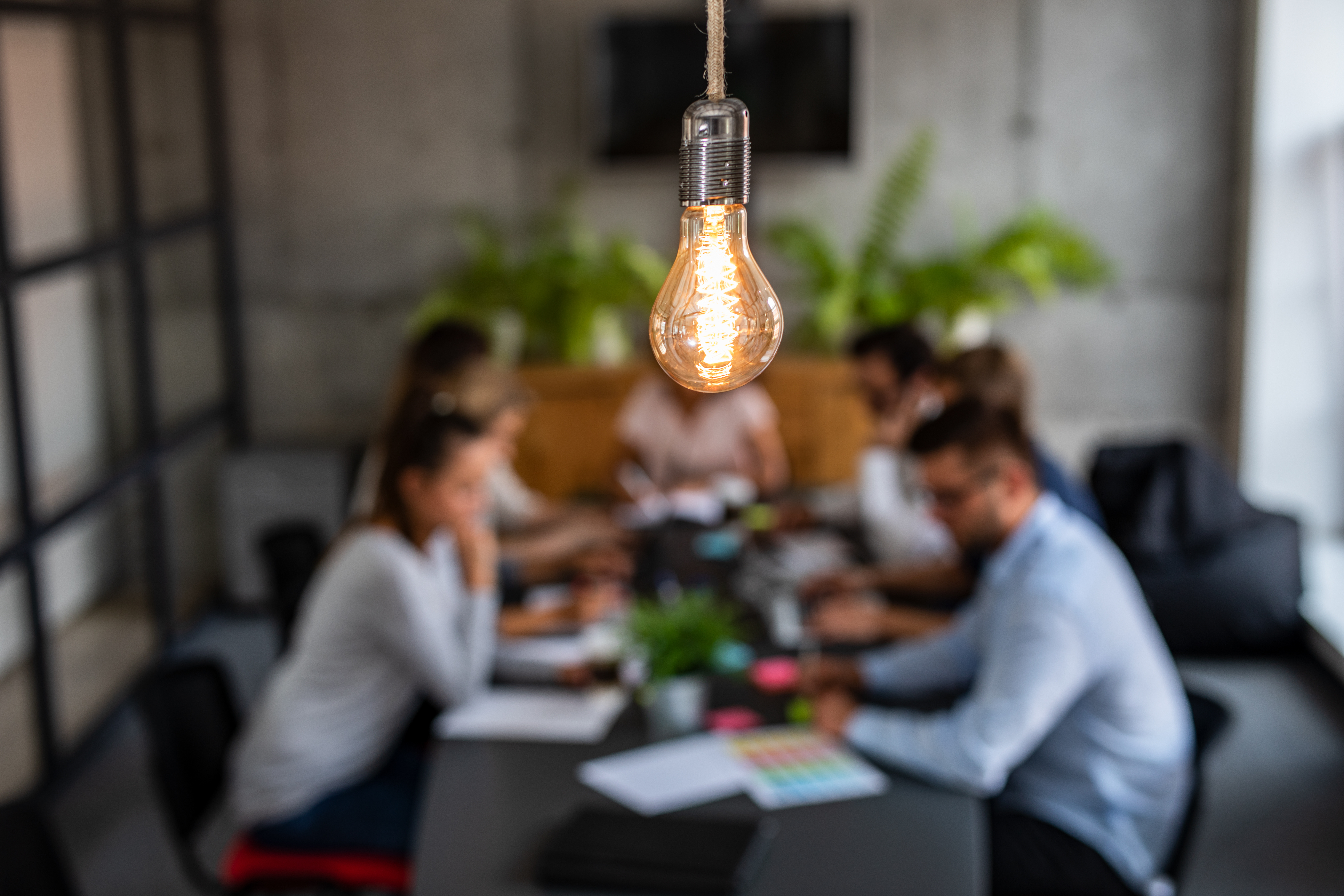 Young creative business people meeting at office. Young business people are discussing together a new startup project. A glowing light bulb as a new idea.